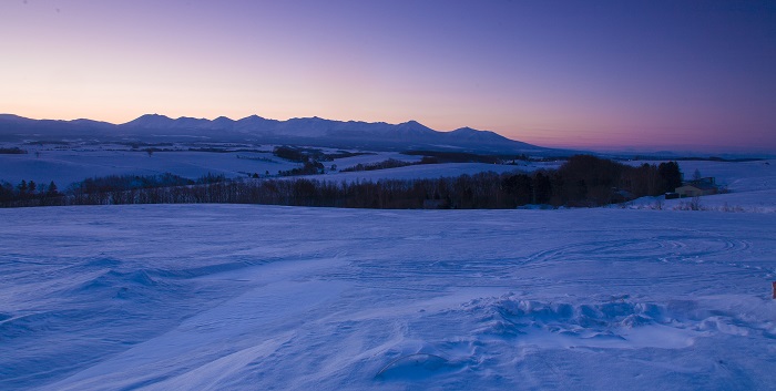 Un paisaje nevado con el atardecer de fondo 