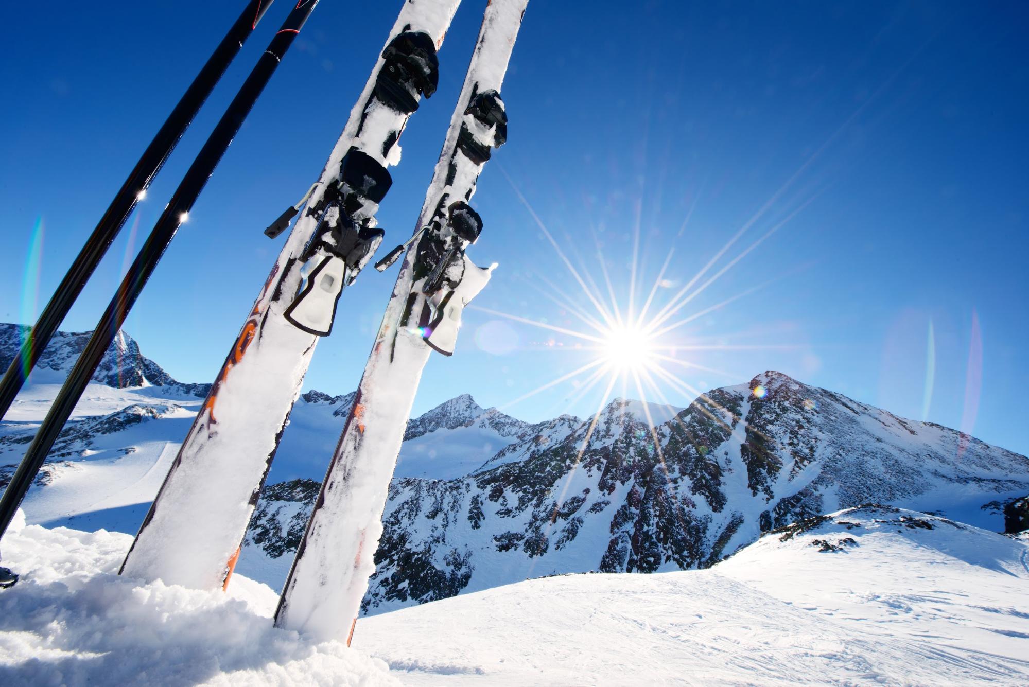 Esquís plantados en la nieve con el sol de fondo 