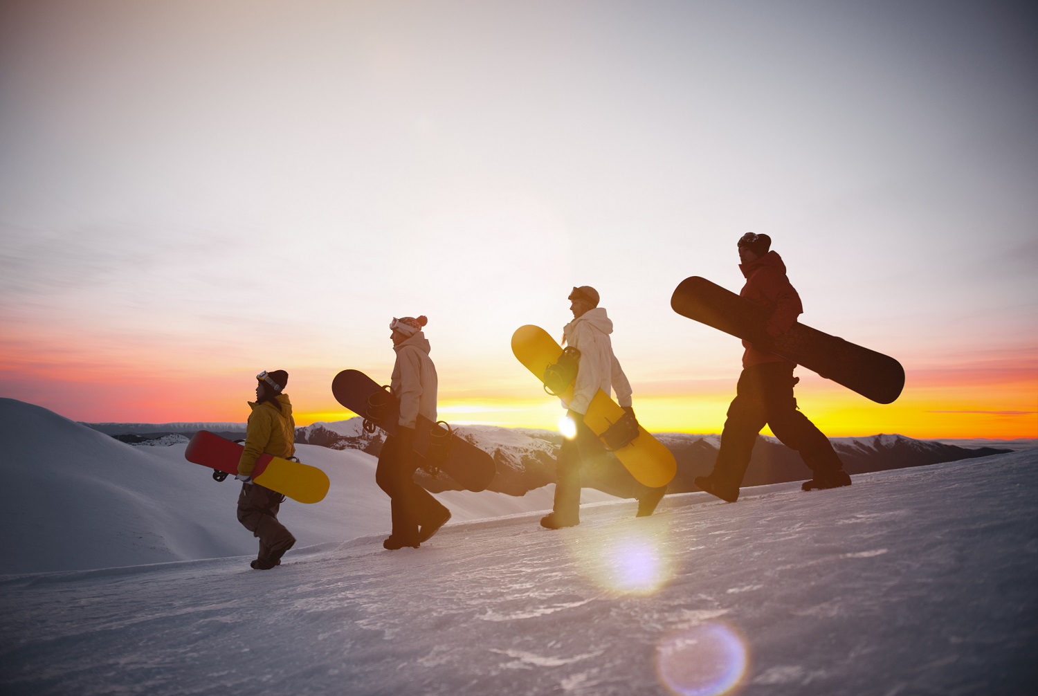 Grupo de esquiadores haciendo snowboard en el atardecer 