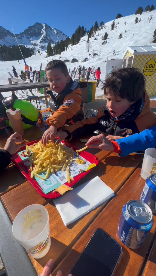 Tres niños comiendo patatas fritas en una estación de esqui 