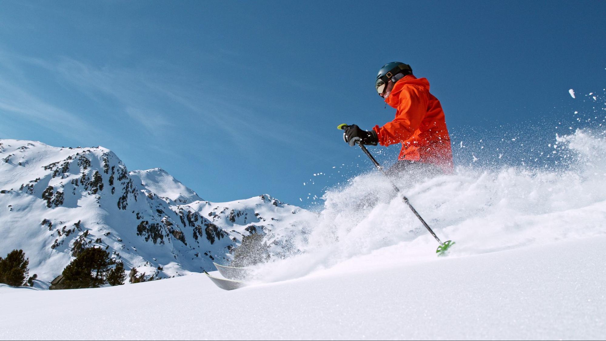 Hombre haciendo freeride en la nieve con las montañas de fondo 